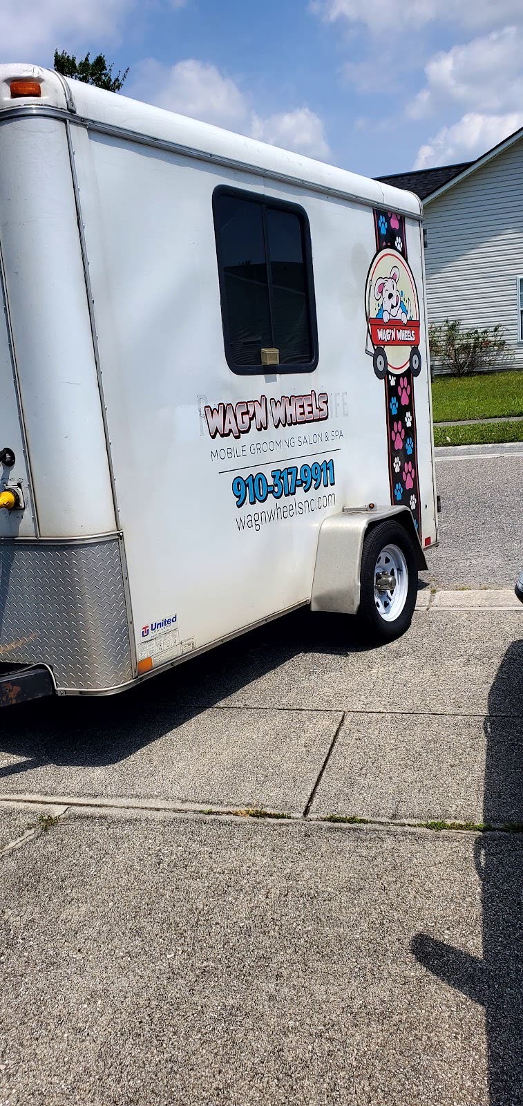 The Wag'N Wheels mobile grooming trailer parked on a driveway